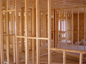 Interior framing of a wooden house under construction, showing unfinished walls and beams.