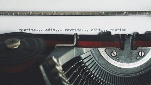 Close-up of a typewriter with the typed words 'rewrite... edit... rewrite... edit... rewrite.'