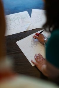 Person sketching architectural plans on paper, with a ruler and drawing tools.