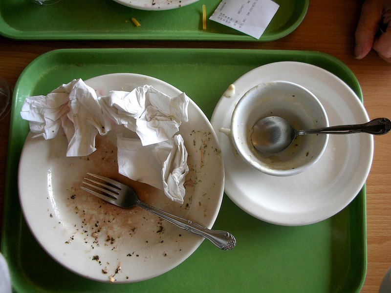 Dirty dishes stacked on a green lunch tray.