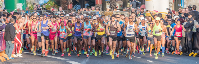A diverse group of marathon runners including both men and women, dressed in colorful athletic gear, participating in a marathon. The scene is outdoors with spectators lining the sidelines.