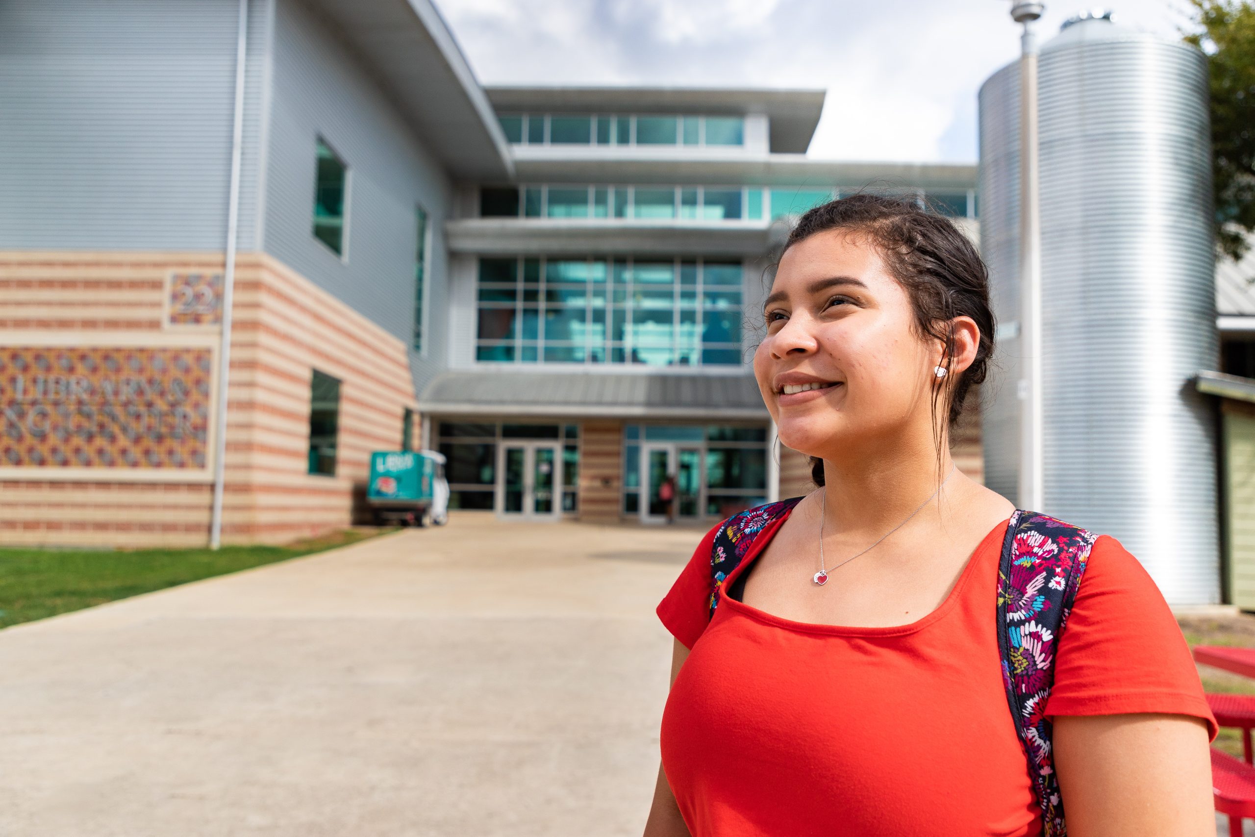 Woman with backpack stands outside of a classroom building.