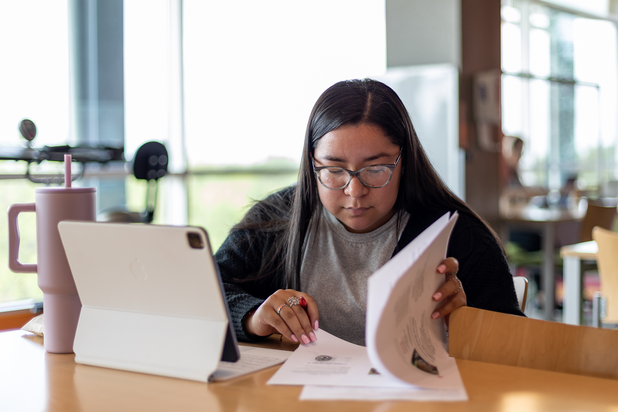 A student sitting at a desk and studying from a textbook.