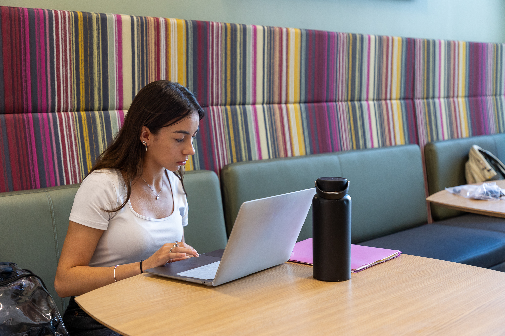 A woman working on her laptop in a common study area.
